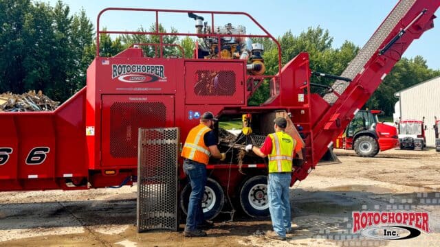 Operators change the screen on a Rotochopper horizontal grinder. The Rotochopper, Inc. logo is in the bottom right corner.